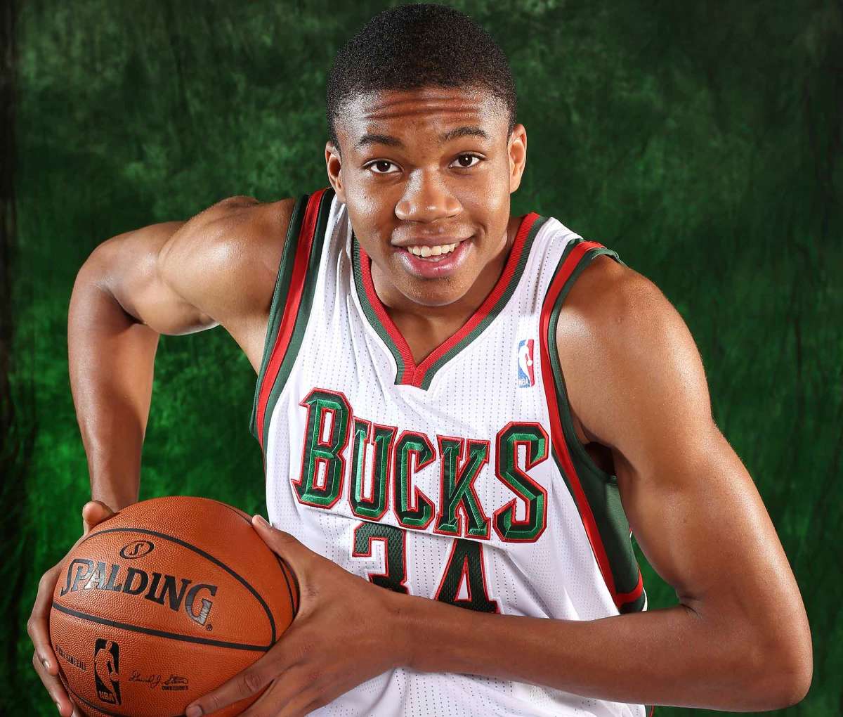 Joven Giannis Antetokounmpo con la camiseta de los Bucks, temporada rookie 2013, sosteniendo un balón Spalding