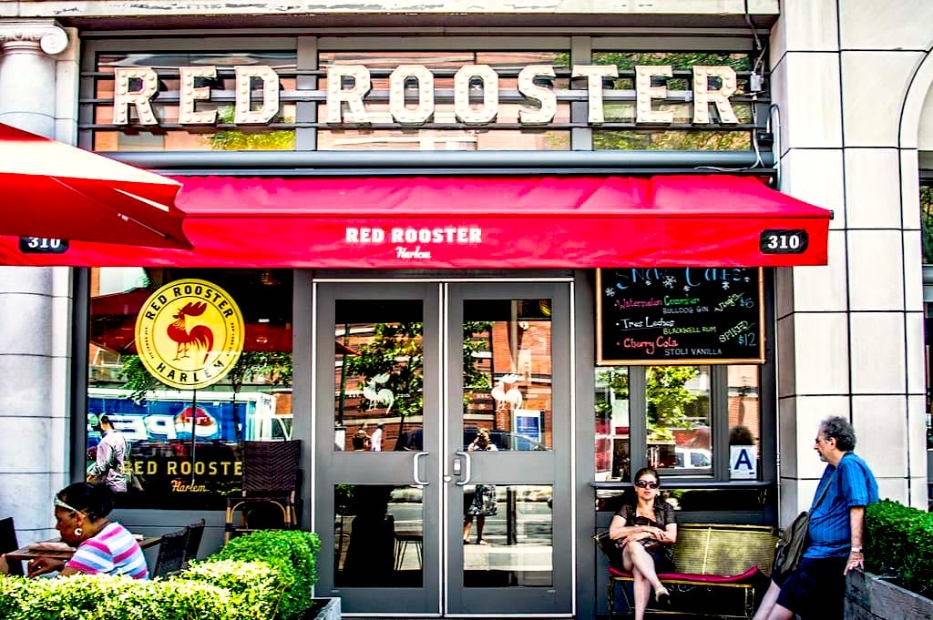 Façade du Red Rooster, restaurant emblématique de Harlem avec terrasse et store rouge