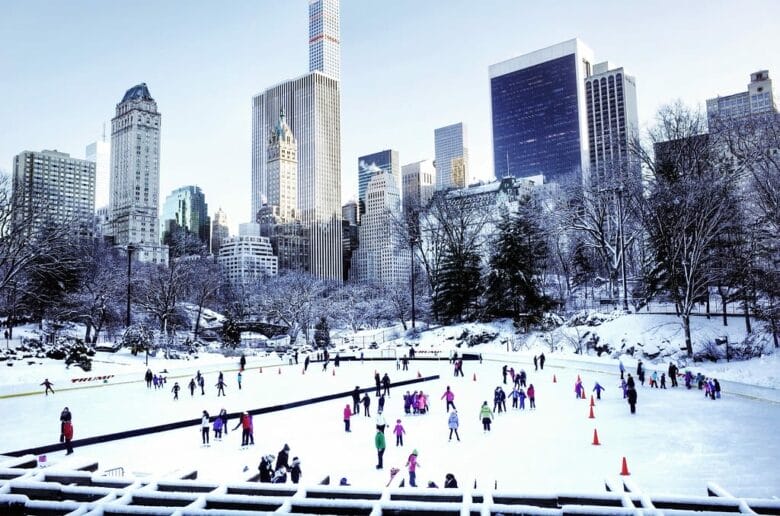 Patinadores en la Wollman Rink de Central Park nevado, skyline de Midtown Nueva York en el fondo