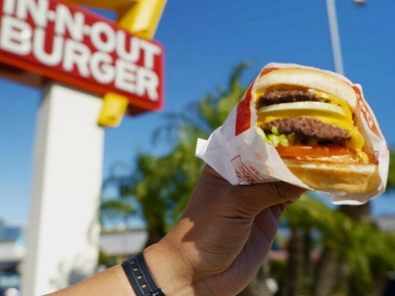 Hamburguesa de In-N-Out Burger delante del cartel de un restaurante en Estados Unidos.