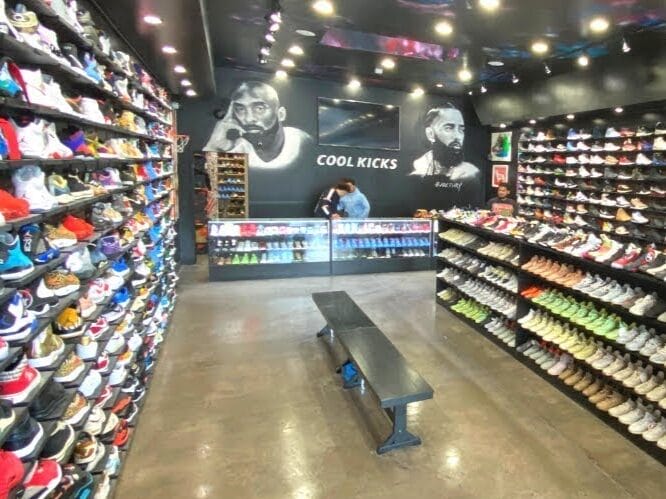 Interior de CoolKicks en Melrose Avenue, Los Angeles, con paredes llenas de sneakers y murales de Kobe Bryant y Nipsey Hussle.