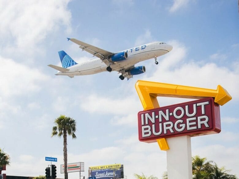 Cartel de In-N-Out Burger con un avi&oacute;n volando por encima cerca del aeropuerto de Los &Aacute;ngeles.