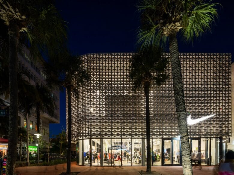Fachada iluminada de Nike Lincoln Road en Miami Beach, una tienda destacada para comprar sneakers en Miami.