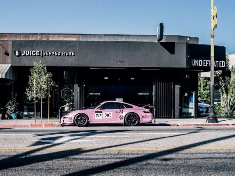 Fachada de UNDEFEATED Silver Lake en Los Angeles, con escaparate negro y un coche rosa aparcado en Sunset Boulevard.