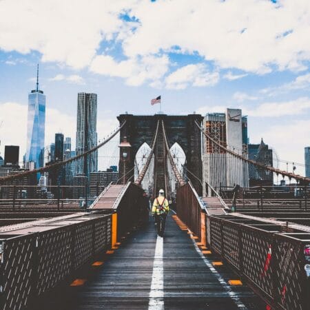 Iconic Brooklyn Bridge view with New York City skyline and construction worker.